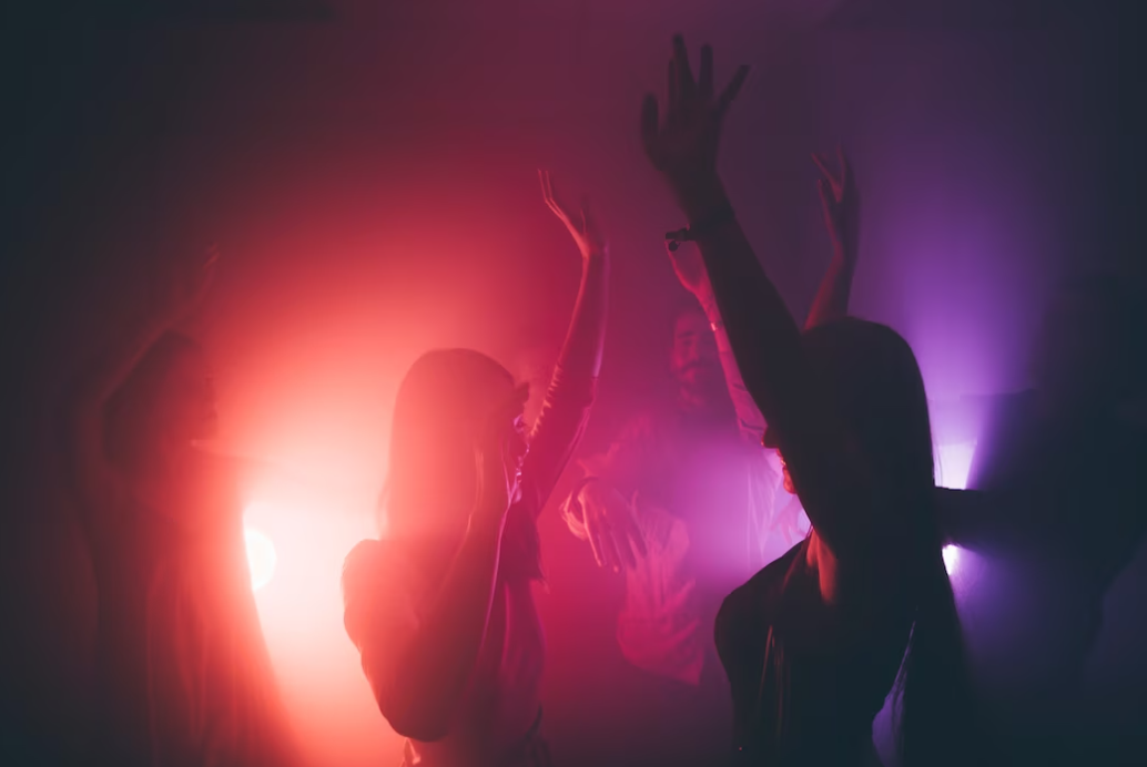 a silhouette of woman dancing in club under pink and red light